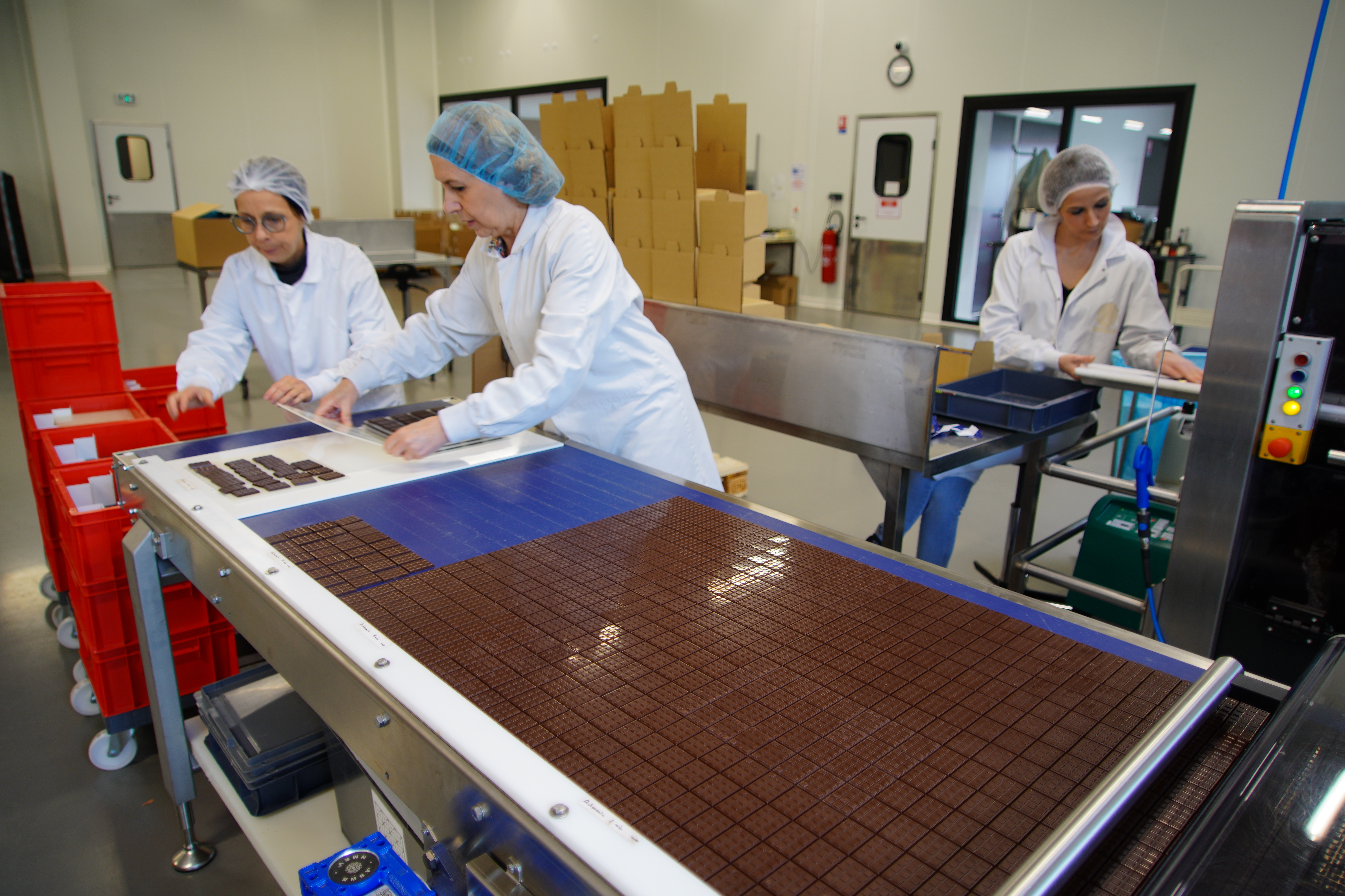 DuPLESSIS' operators packaging small chocolate bars on the Lareka BTB25 with buffer belt with dropping station